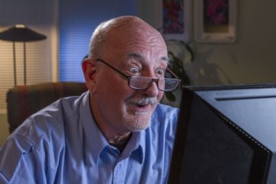 anziano pensionato che guarda sorpreso il computer