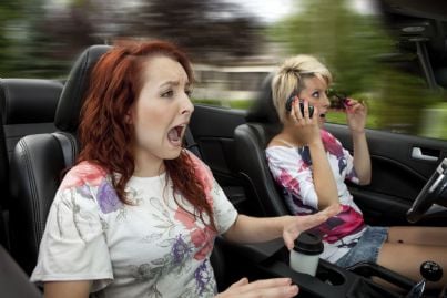 donna alla guida distratta con telefono 