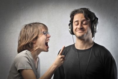 moglie che grida arrabbiata mentre marito ignora ascoltando musica