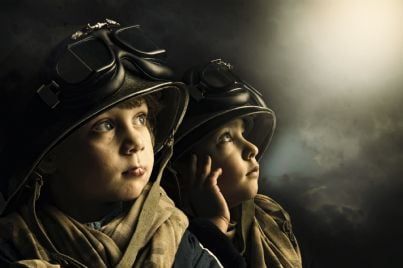 Due bambini in abito militare che guardano il cielo