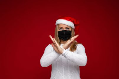 donna con mascherina e cappello di babbo Natale incrocia le braccia