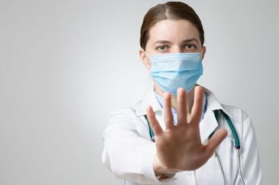 medico donna con mascherina fa stop con la mano