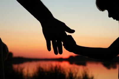 mano del genitore in quella del figlio al tramonto